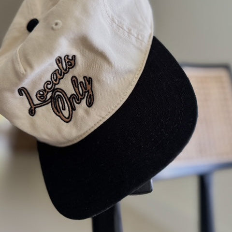 Two-tone cap with 'Locals Only' embroidery on a stand.