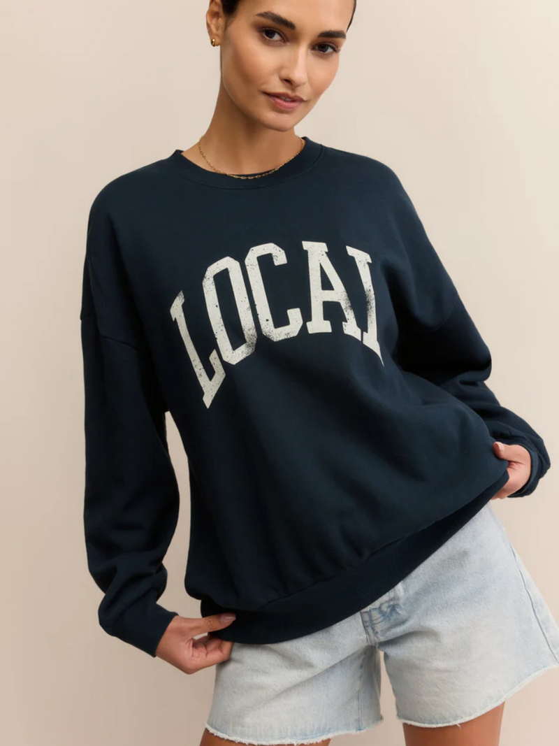 Person wearing a navy sweatshirt with 'LOCAL' printed on it against a beige background